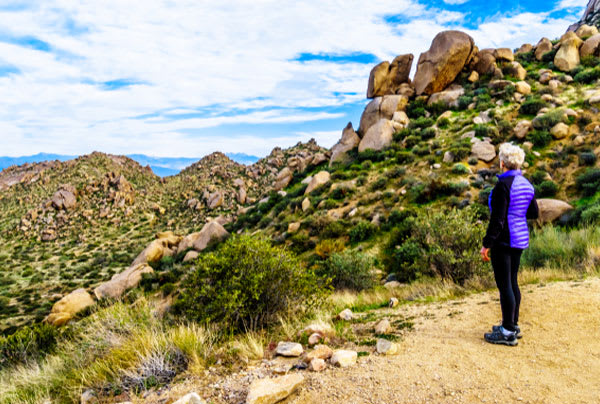 A senior woman on an outcrop looks out at the Arizona desert