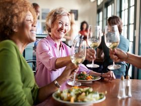 A group of senior women toasting with wine glasses